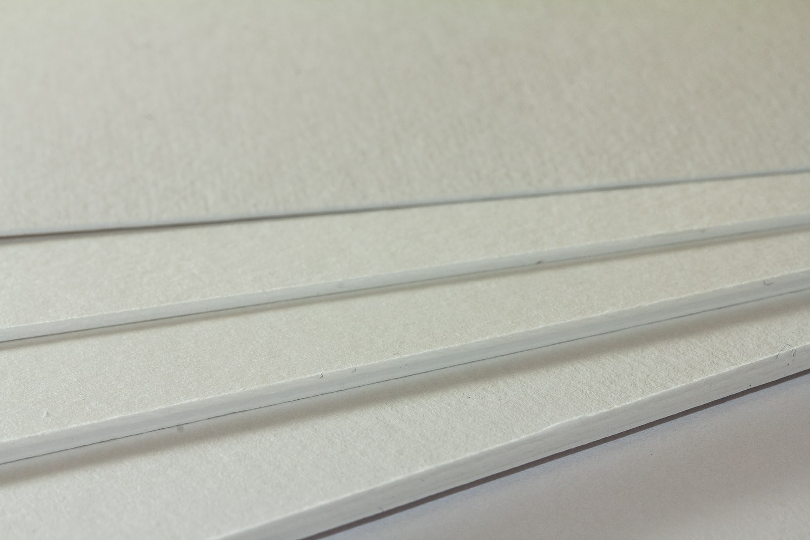 Eine Nahaufnahme der Oberflächenstruktur unseres Rückwandkarton hellweiß in vier verschiedenen Stärken